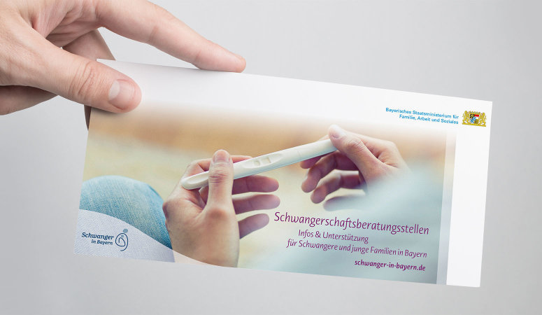 Eine Hand hält die Broschüre „Schwangerschaftsberatungsstellen Infos & Unterstützung für Schwangere und junge Familien in Bayern“