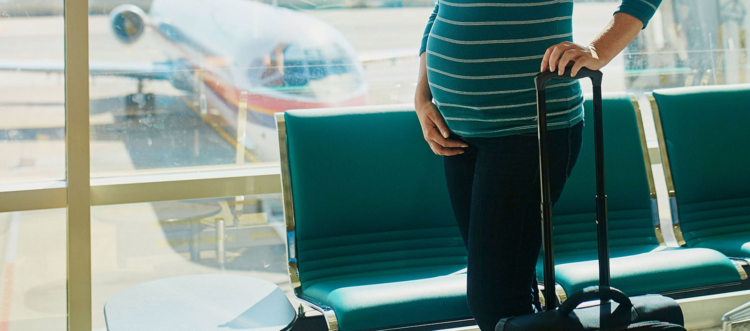Schwangere Frau in Abflughalle eines Flughafens. 