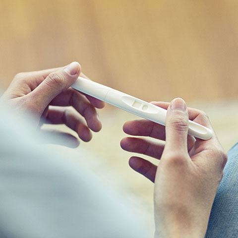 Frau hält Schwangerschaftstest in den Händen. 